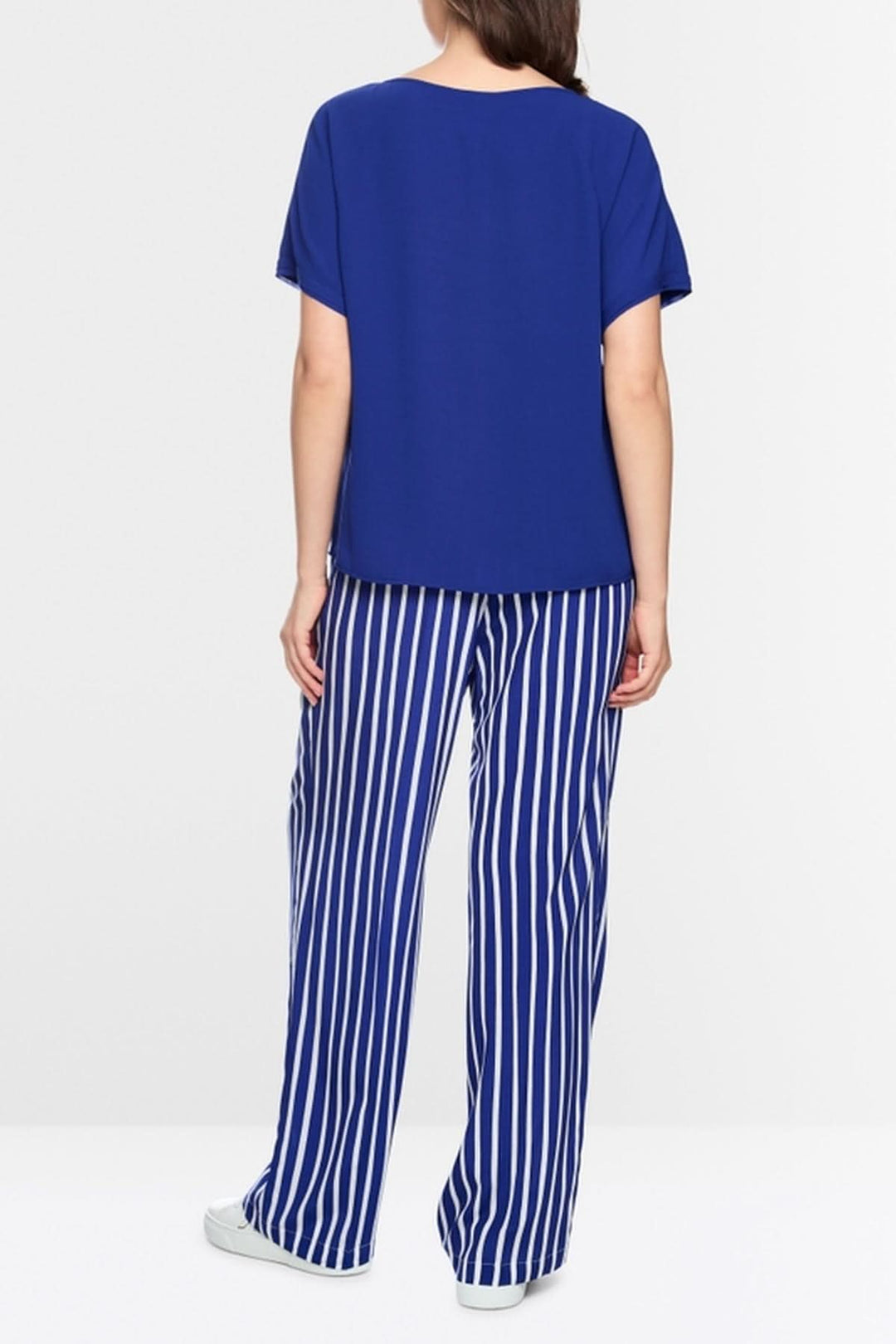 Vue arrière d'une blouse ample en tissu fluide bleu avec manches courtes, combinée à un pantalon rayé vertical bleu et blanc.