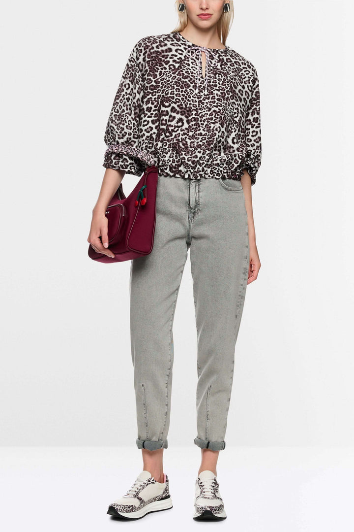 Blouse avec imprimé léopard moderne, ample, avec élastiques ajustables et encolure en V, portée par mannequin.