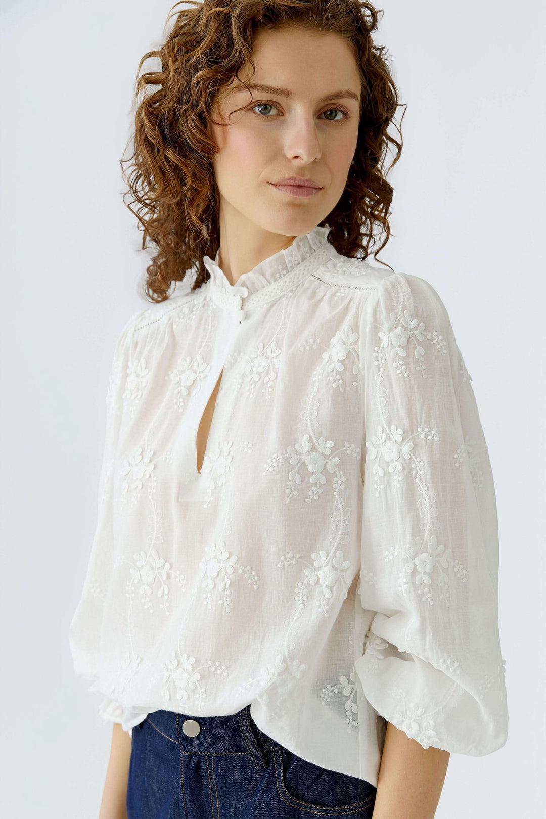 Blouse à broderies florales avec col montant froncé et silhouette élégante, parfaite pour un style quotidien ou habillé.
