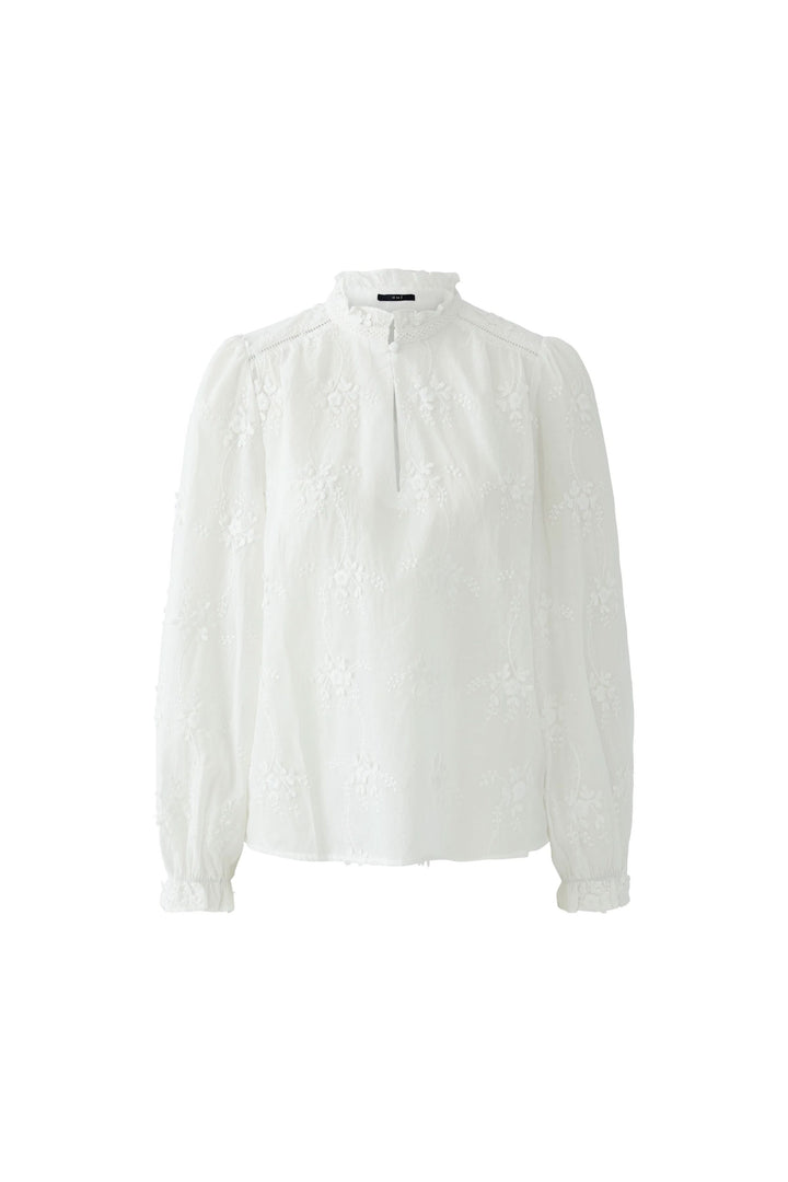 Blouse à broderies florales blanche avec col montant et manches longues, idéale pour un look élégant et féminin. Décris moi le produit en français.