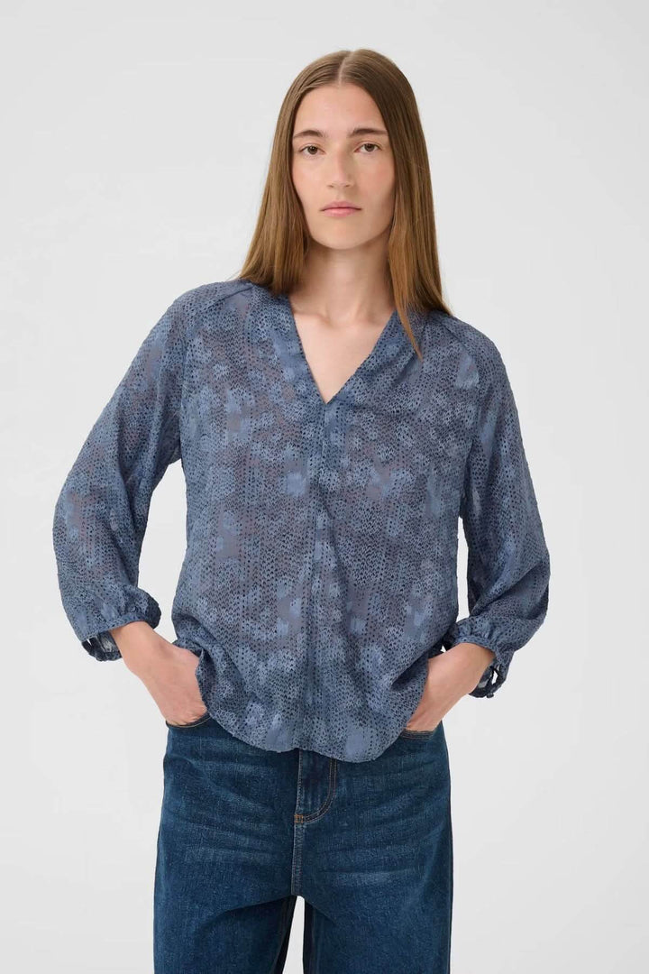 Blouse fluide à col V et manches 3/4 en bleu, parfaite pour un style décontracté et élégant.