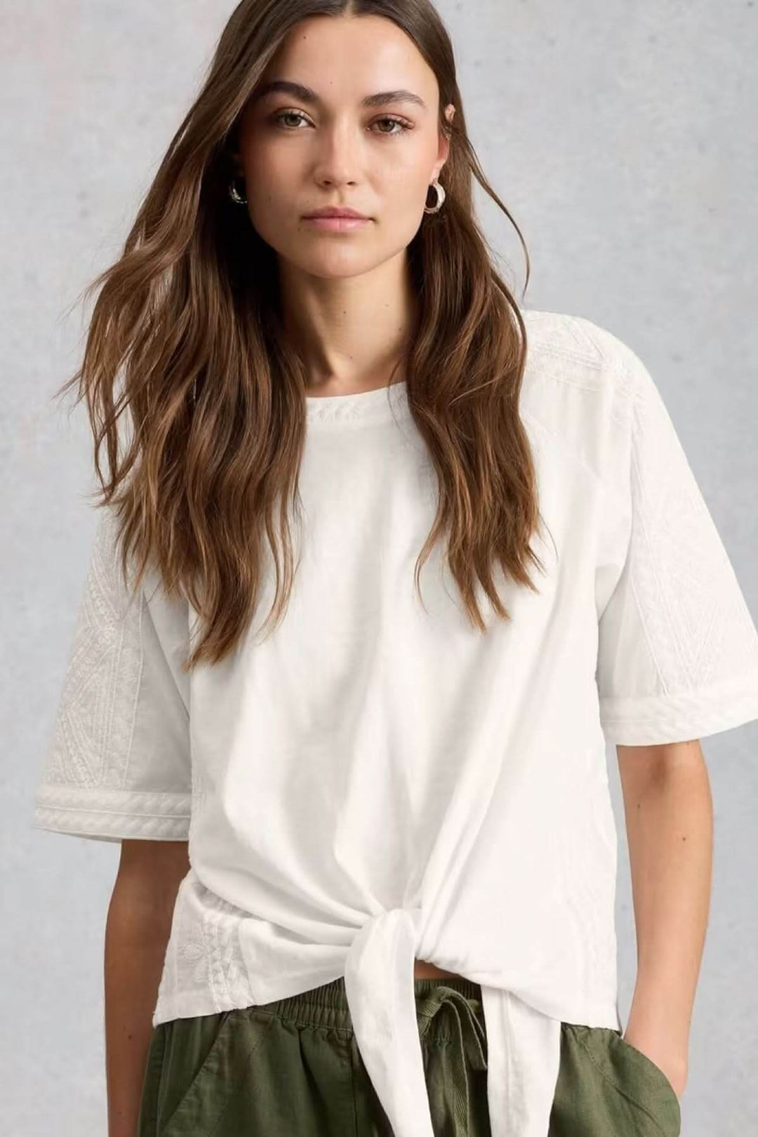 Blouse à col rond brodé avec ourlet à nœud, coupe ample et féminine, manches courtes, idéale pour un look quotidien décontracté.