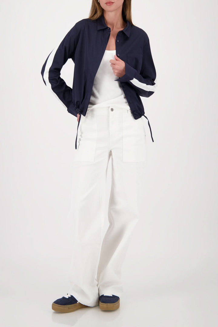 Modèle portant une blouse courte à cordon ajustable, style décontracté moderne, avec une chemise classique et pantalon blanc.