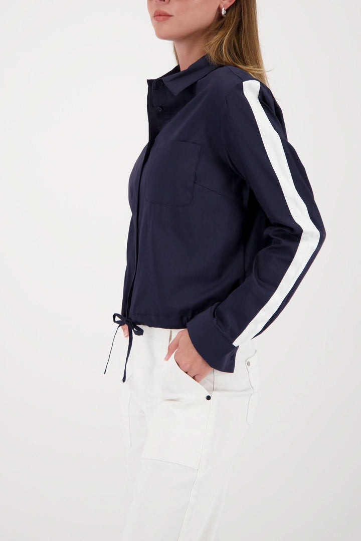 Blouse courte à cordon ajustable avec manches à bandes blanches, portée par une femme, coupe moderne et décontractée.