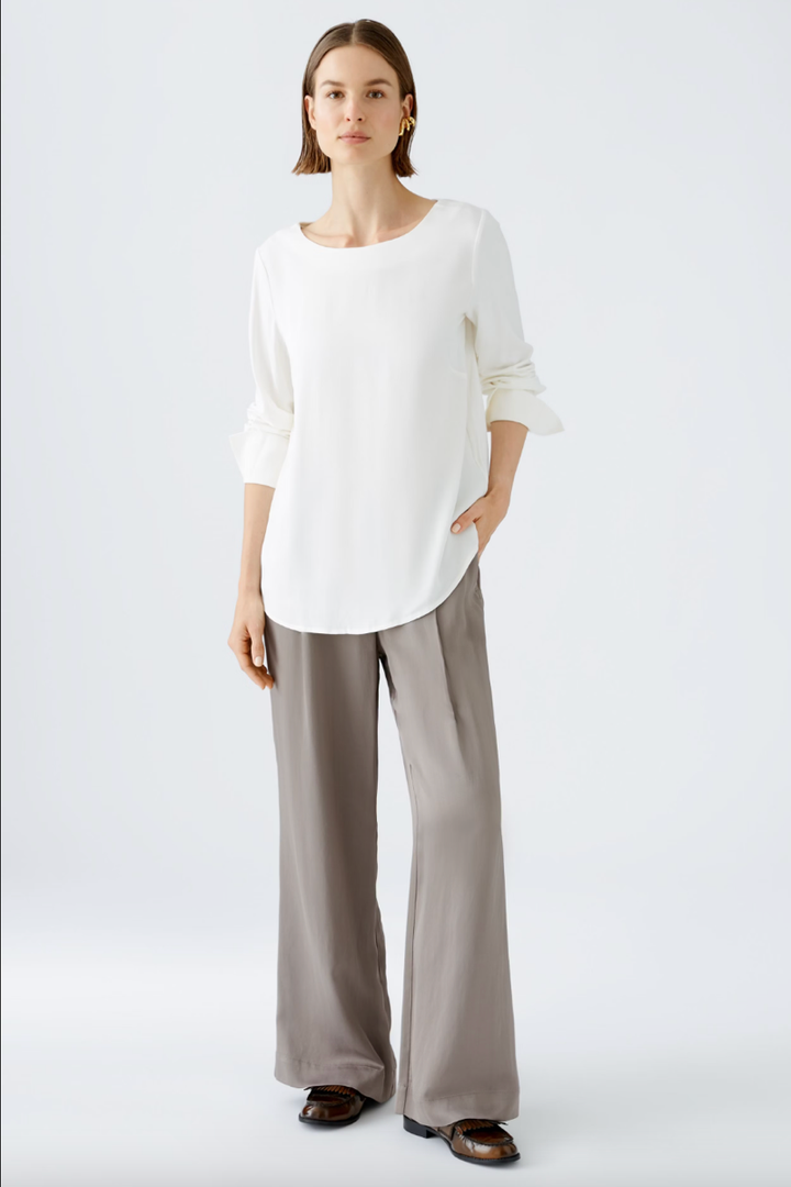 Blouse décontractée blanche en satin avec pantalon gris, style chic et confortable.
