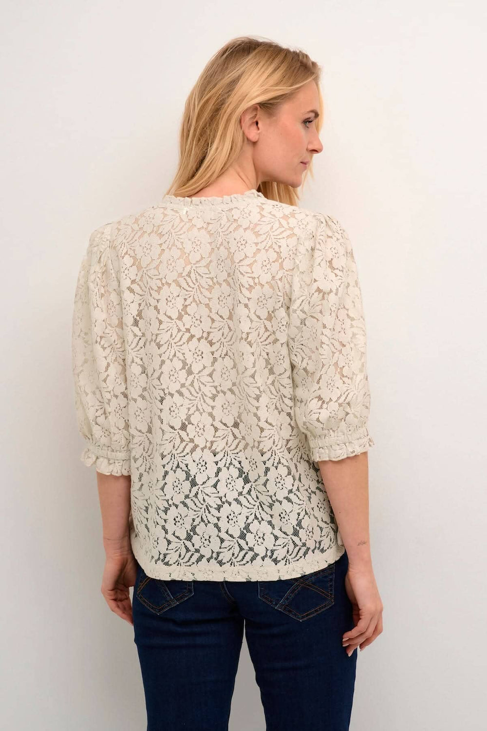 Blouse de Kaspis en dentelle, coupe A, manches trois-quarts, élégante et décontractée, portée avec un jean.