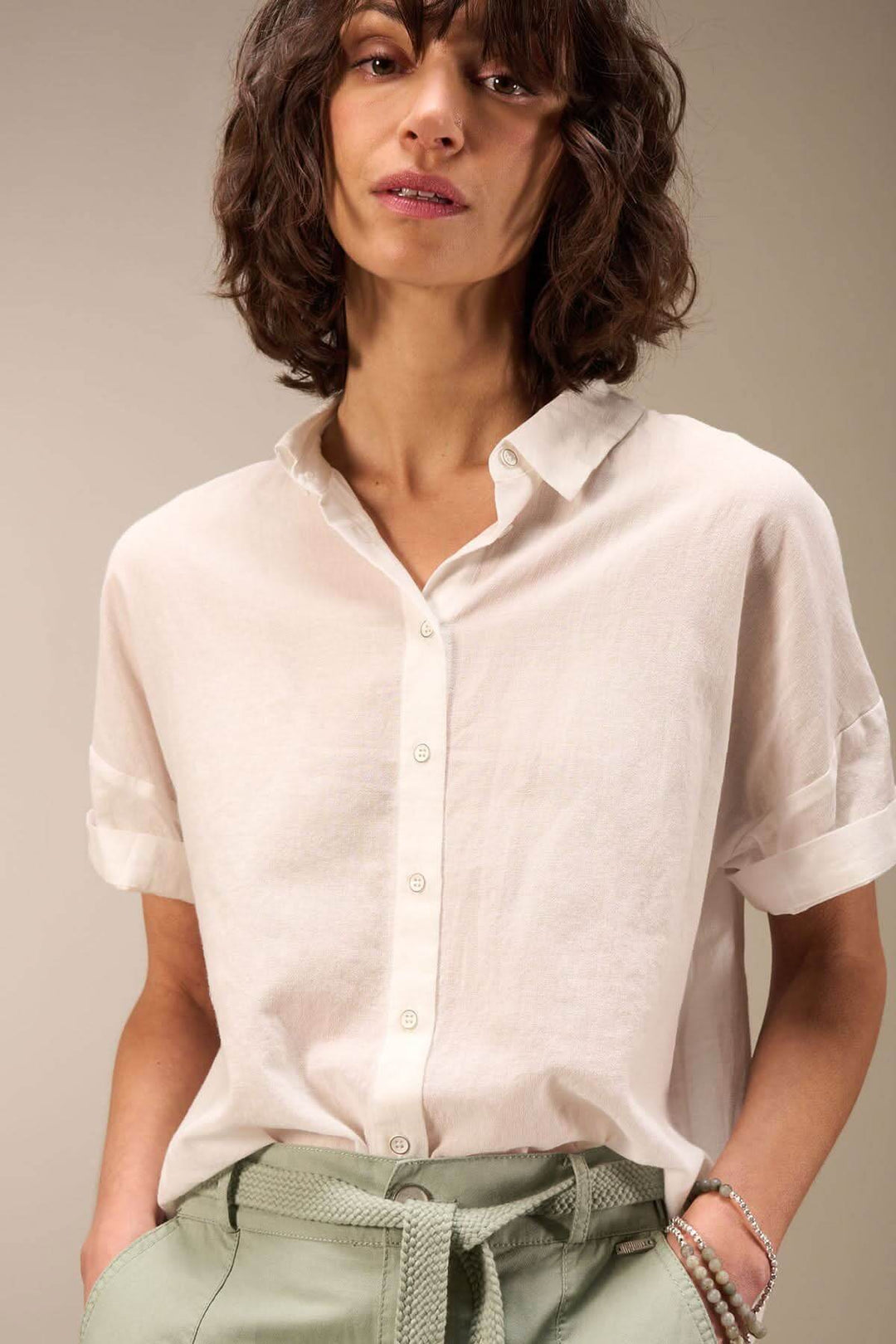 Modèle portant une blouse en coton claire à col chemise et manches courtes, look décontracté et estival.