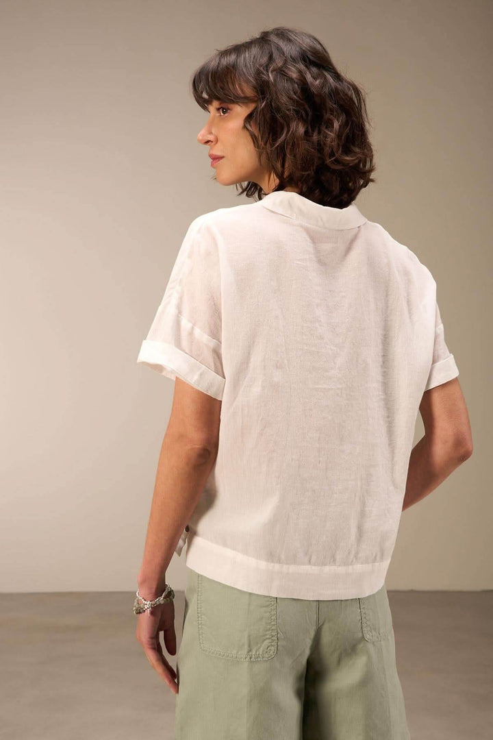 Femme portant une blouse courte en coton biologique, vue de dos, avec col chemise et manches courtes.