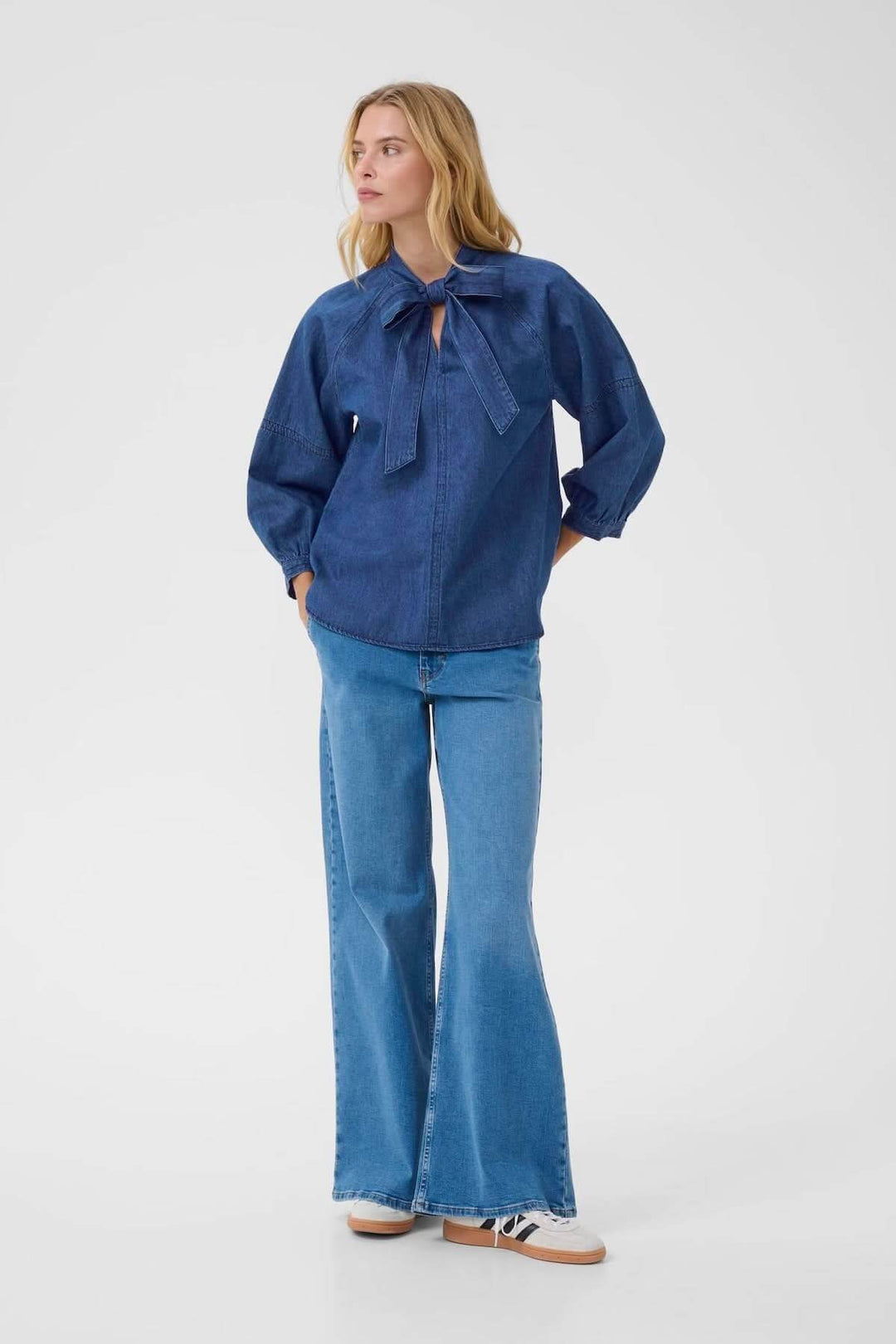 Blouse en denim léger avec col noué et manches trois-quarts, portée avec un jean évasé.