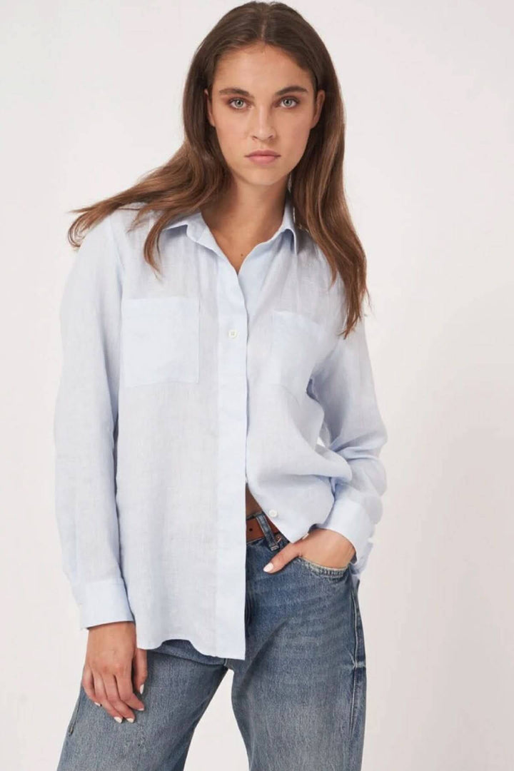 Blouse en lin fluide à manches longues et col classique, offrant un look décontracté et intemporel pour femmes, portée avec un jean casual.