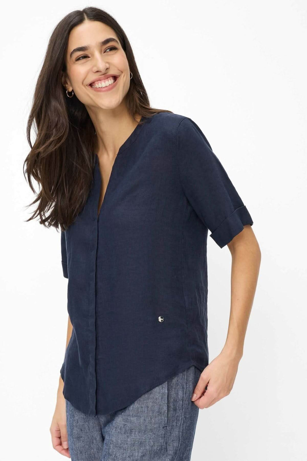 Femme portant une Blouse en lin VERI avec manches courtes et encolure ouverte, design moderne et minimaliste pour un usage quotidien.