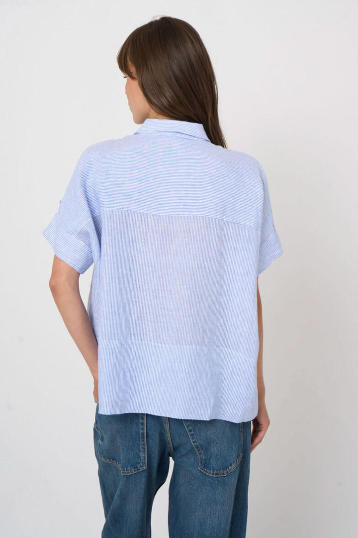 Femme portant une Blouse en lin à rayures fines, vue de dos, manches courtes et coupe fluide.
