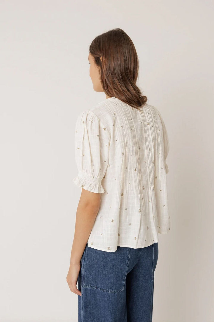 Blouse à encolure dentelle avec détails de plis et manches courtes bouffantes vue de dos portée par modèle.