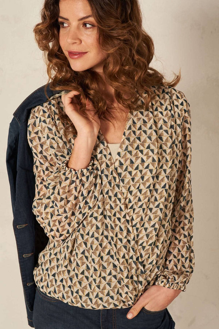 Femme portant une blouse enveloppée à motifs géométriques, avec un décolleté en V et des manches longues.