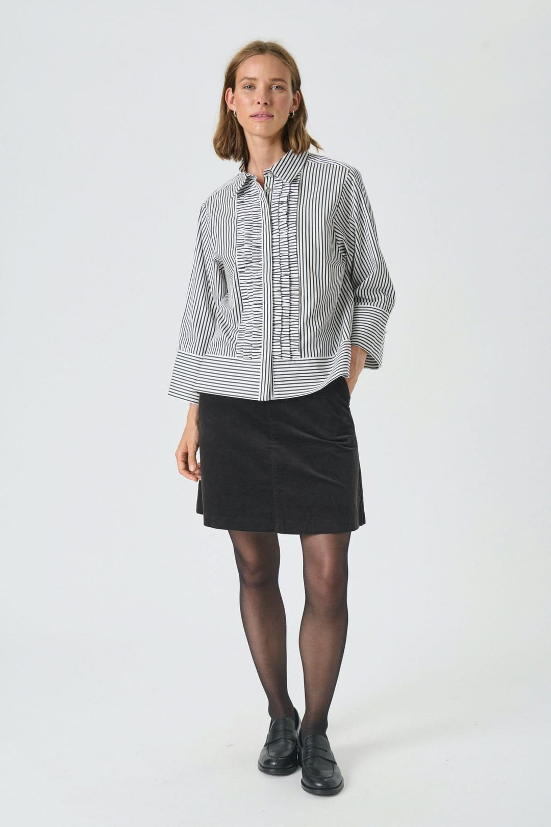 Femme portant la Blouse à fines rayures Vinny avec rayures verticales et volants, style chic-décontracté.