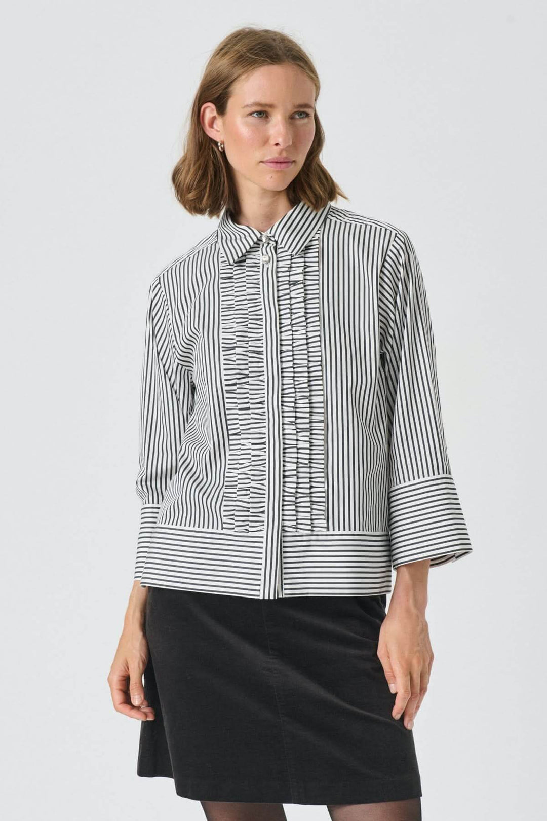 Femme portant la Blouse à fines rayures Vinny, chemise chic avec volants discrets et manches amples, style élégant et professionnel.