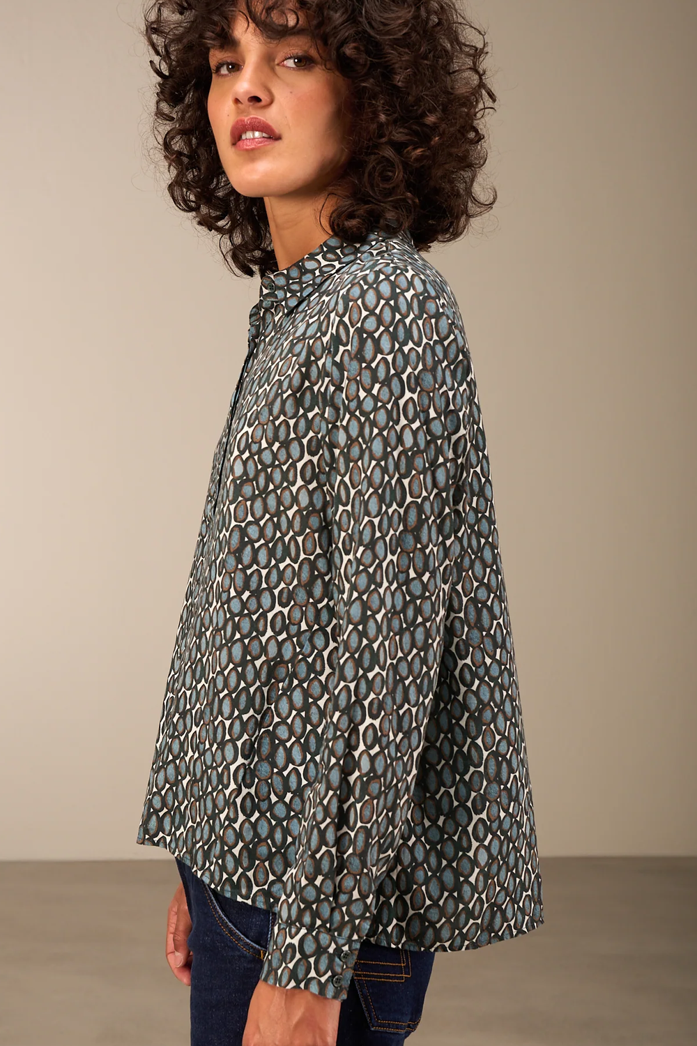 Femme portant une blouse fluide imprimée à col chemise classique et manches longues, idéale pour un style à la fois décontracté et élégant.