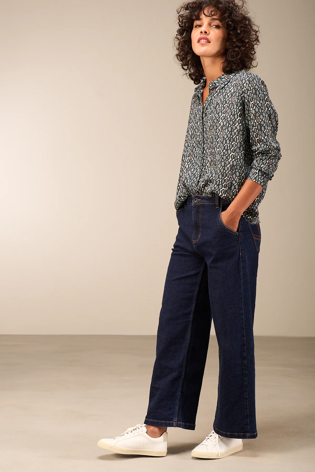 Femme portant une blouse fluide avec col chemise, coupe droite et manches longues, style moderne, confort et élégance au quotidien.