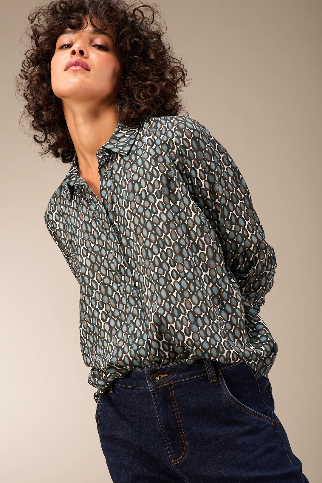Femme portant une blouse fluide avec col chemise classique, style moderne avec pantalon taille haute, tissu léger et élégant.