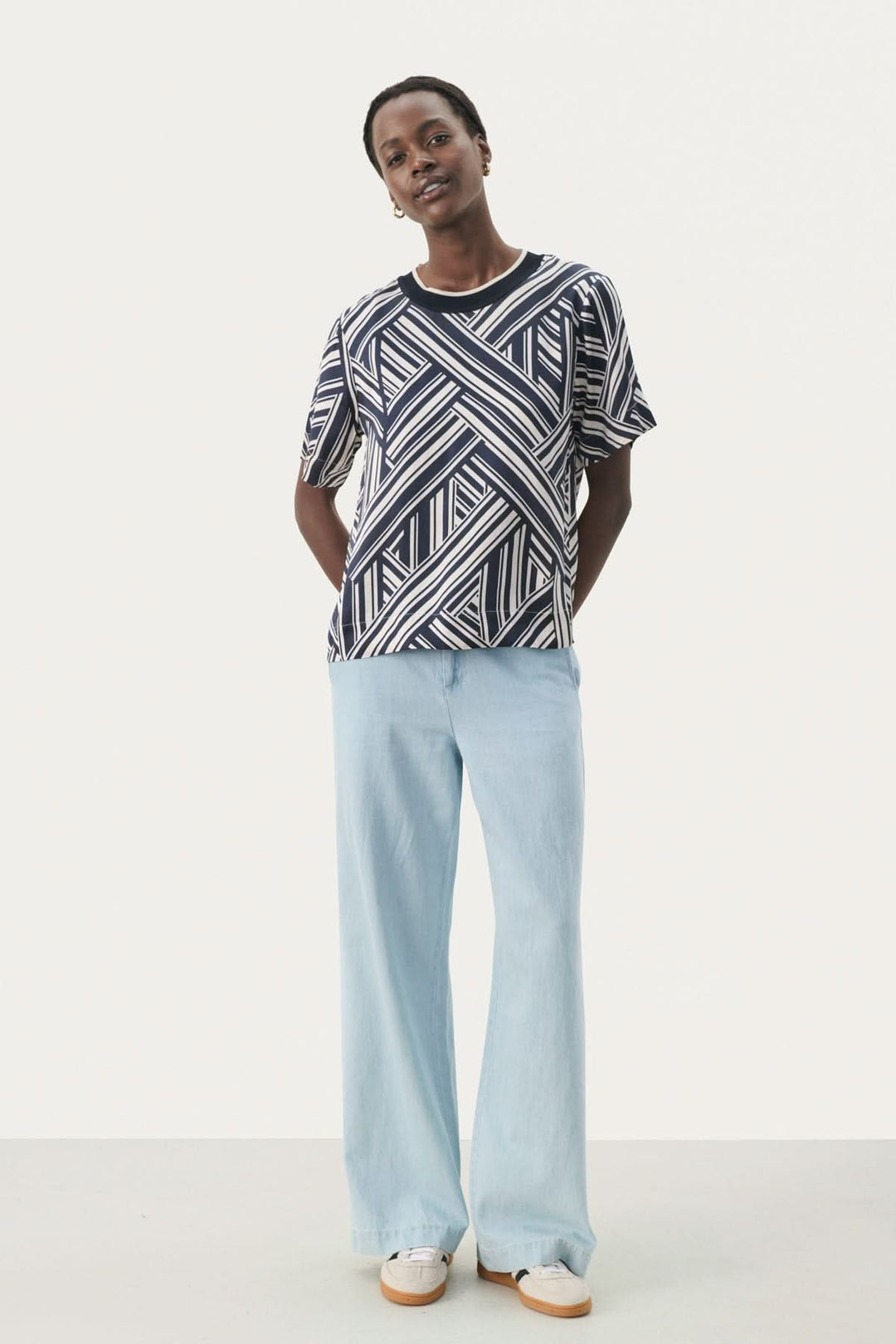 Model wearing a stylish geometric pattern blouse with loose light blue pants, showcasing a relaxed and chic outfit.