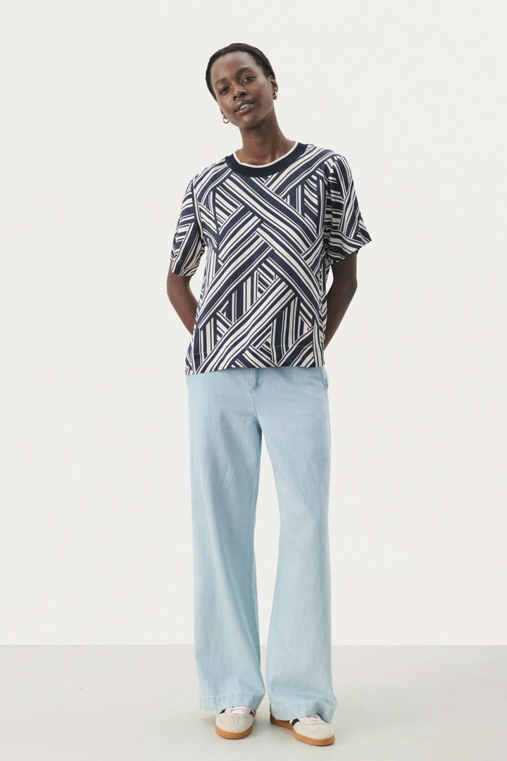 Model wearing a stylish geometric pattern blouse with loose light blue pants, showcasing a relaxed and chic outfit.