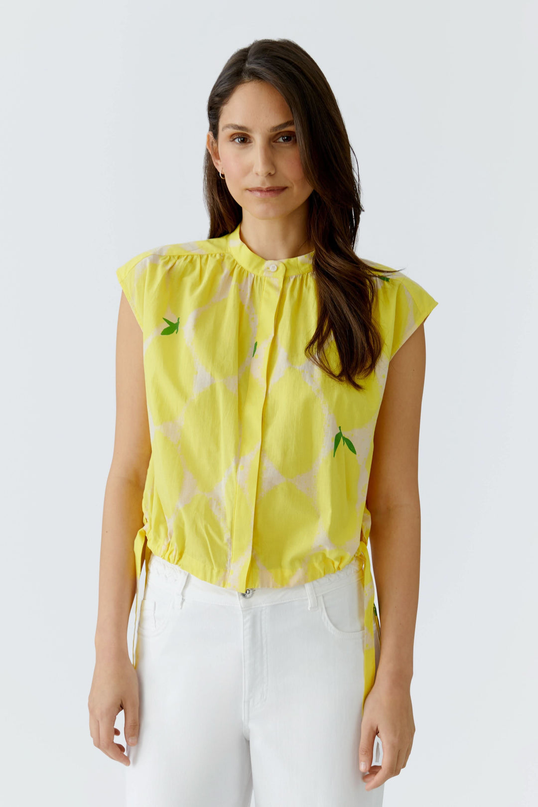 Femme portant une blouse fluide à col montant jaune, sans manches, idéale pour un look élégant et décontracté.
