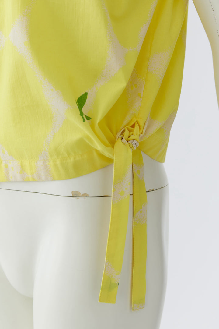 Blouse fluide à col montant jaune avec détail de nœud latéral sur mannequin, idéal pour look estival élégant.
