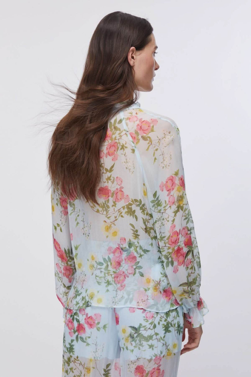 Femme portant une blouse fluide à imprimé floral avec manches longues et encolure en V, en tissu léger et élégant.