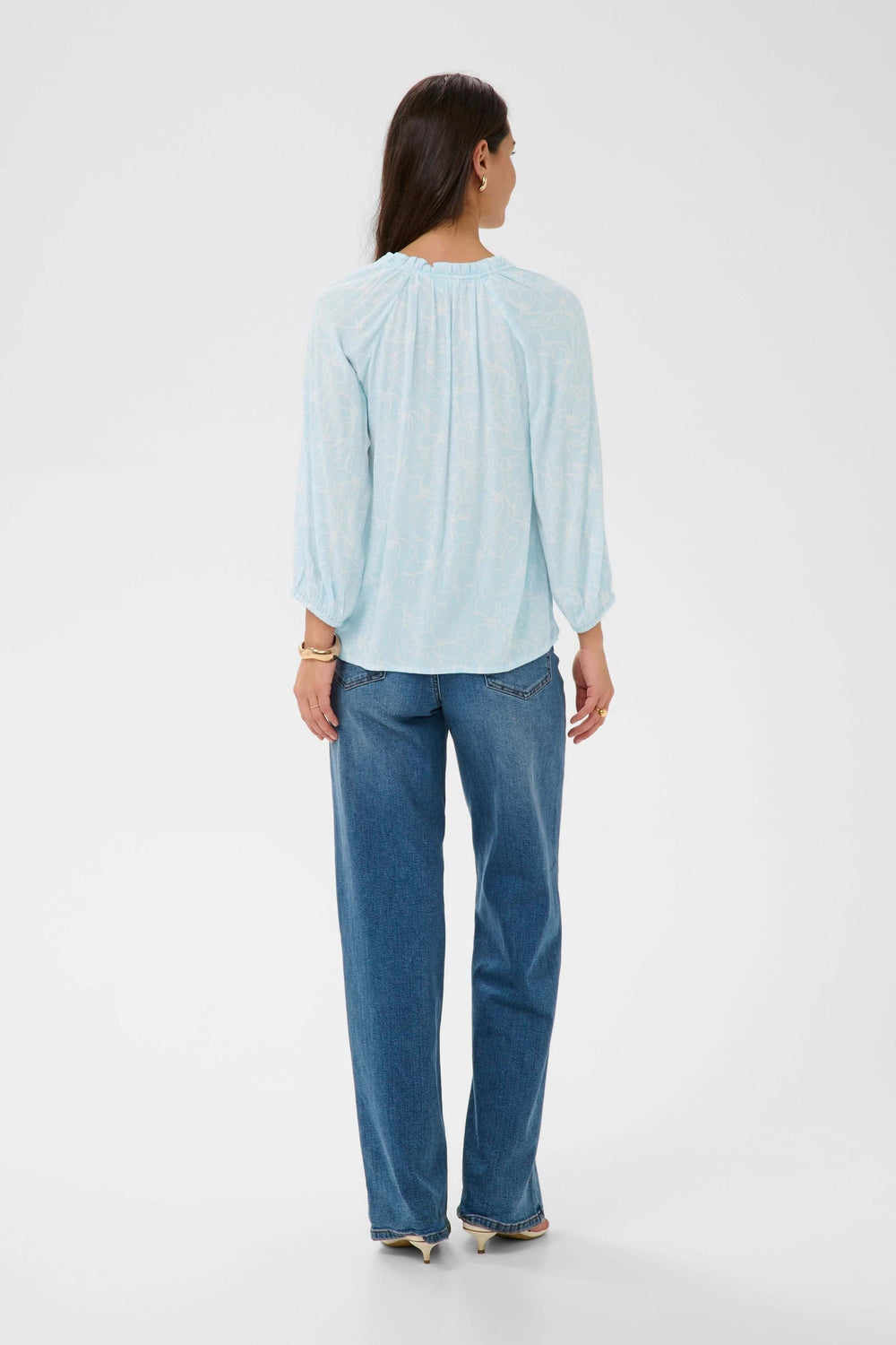 Vue arrière d'une blouse fluide à imprimé floral discret avec manches trois-quarts et encolure froncée.