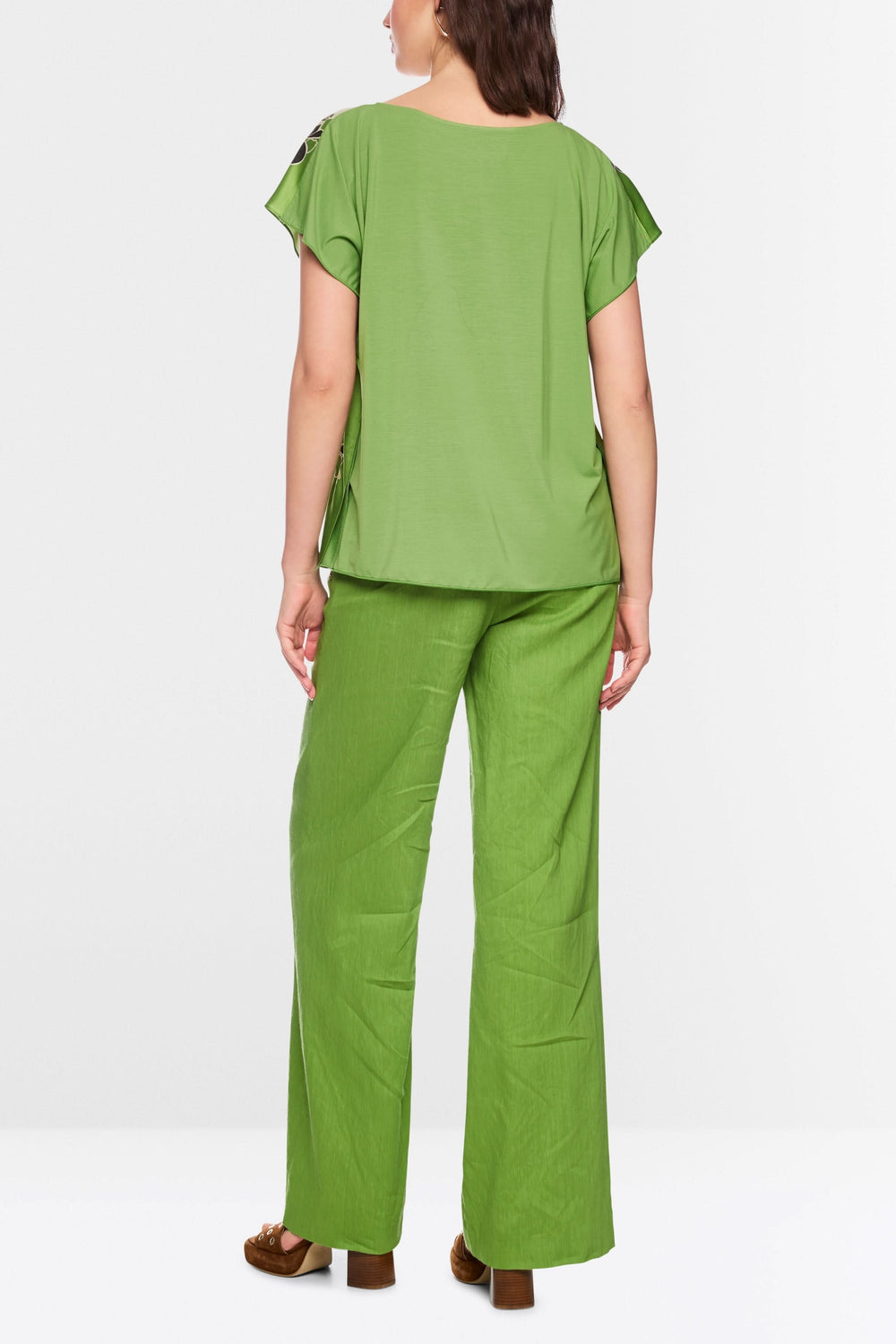 Person wearing a green Blouse fluide imprimée with short sleeves, seen from the back, highlighting the fluid and artistic design.