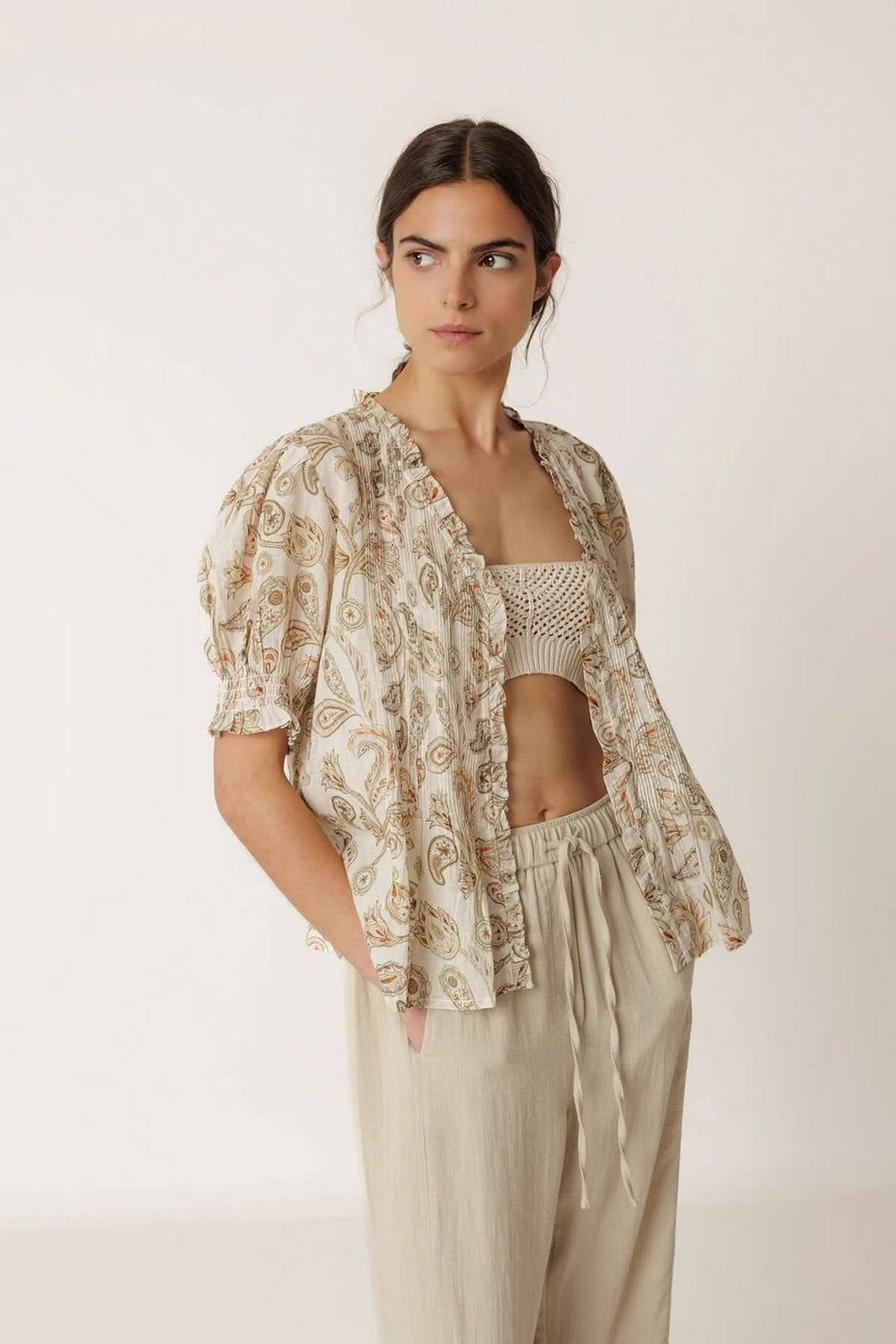 Blouse fluide imprimée à manches courtes avec motifs délicats, portée par un mannequin, mettant en valeur les manches courtes et encolure travaillée.