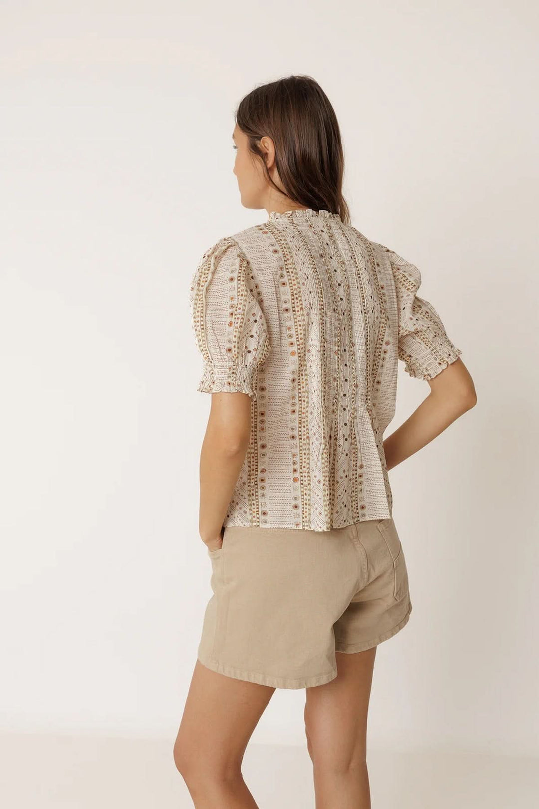 Femme portant une blouse fluide imprimée à manches courtes avec encolure en V et manches bouffantes, vue de dos.