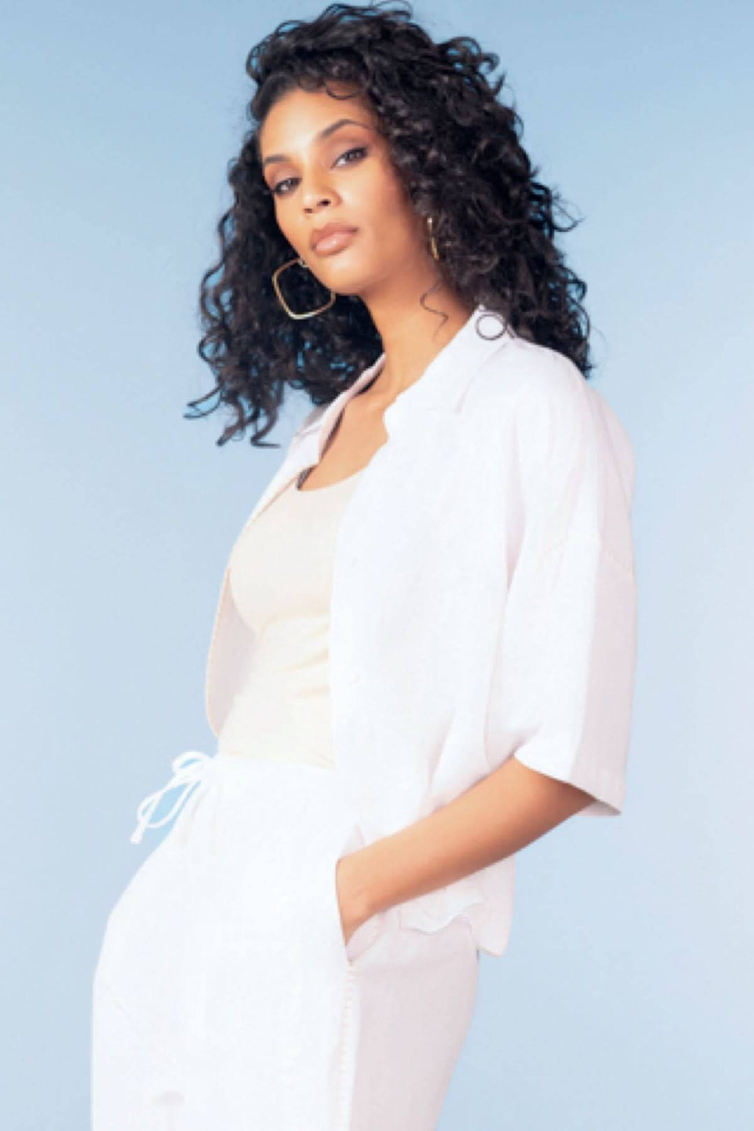 Femme portant une blouse fluide manches courtes blanche élégante et décontractée, avec coupe droite et tissu aérien pour un style moderne.