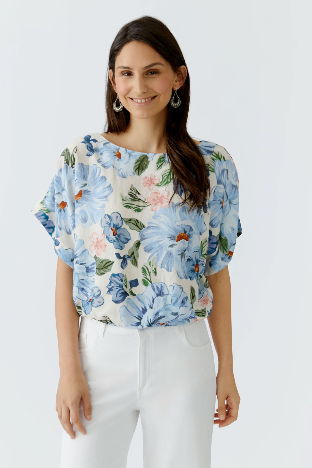 Modèle portant une blouse fluide à manches courtes à motif floral, idéale pour un style élégant et décontracté.
