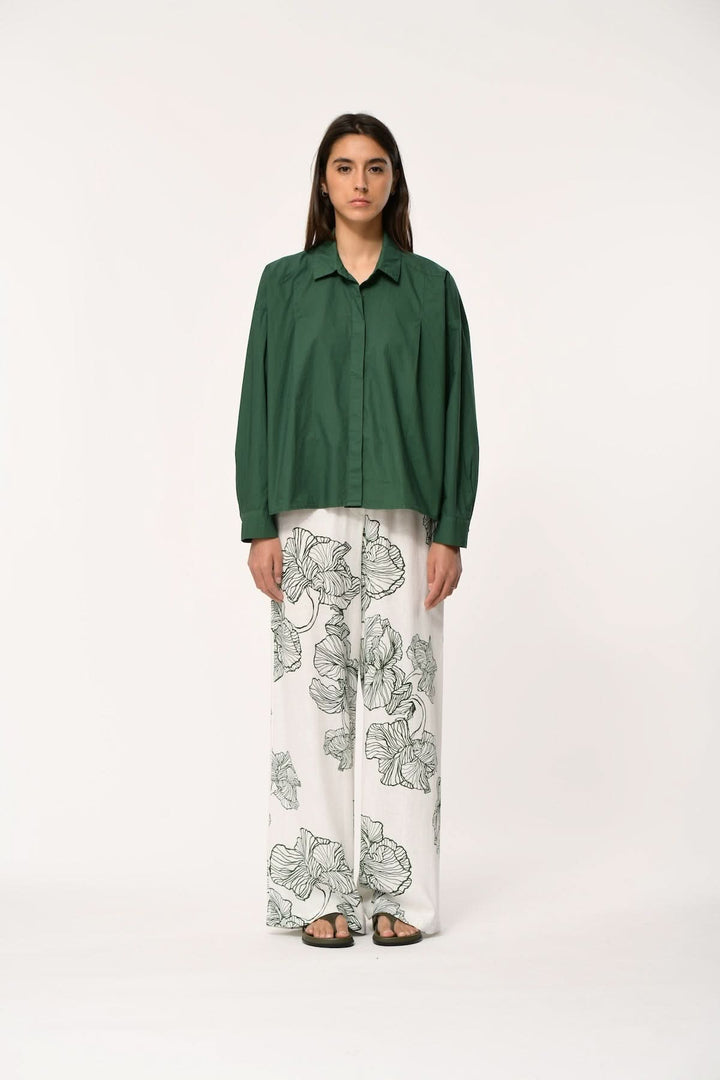 Blouse fluide à manches longues BISMA avec col chemise, portée avec un pantalon floral pour un look moderne et élégant.