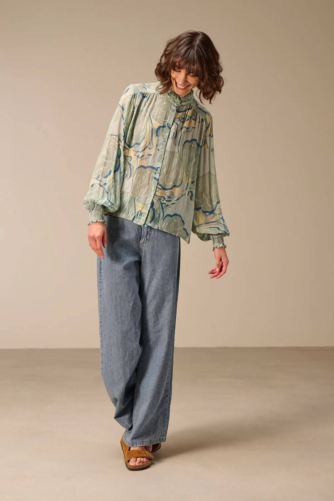 Blouse fluide à manches longues en tissu fluide avec motif, portée avec un col montant et manches volumineuses, idéale pour mi-saison.