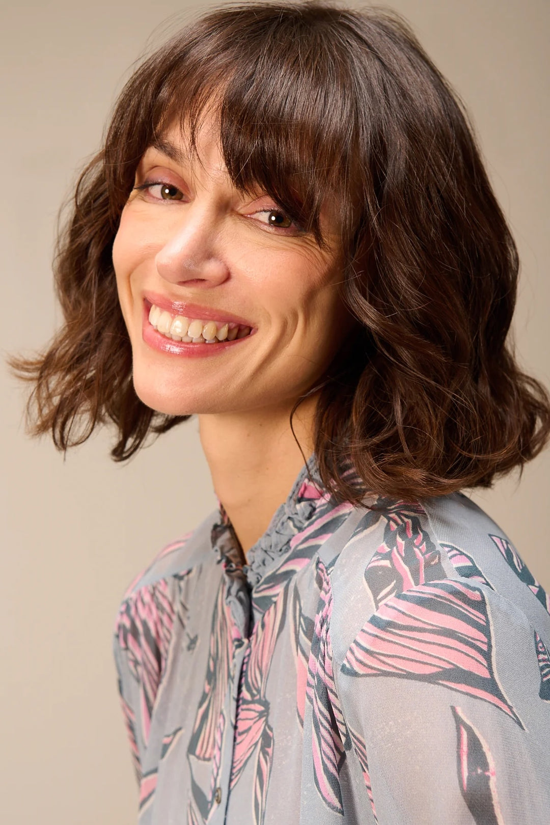 Femme portant une blouse fluide à manches longues avec un col montant et imprimé floral abstrait, idéal pour la mi-saison.