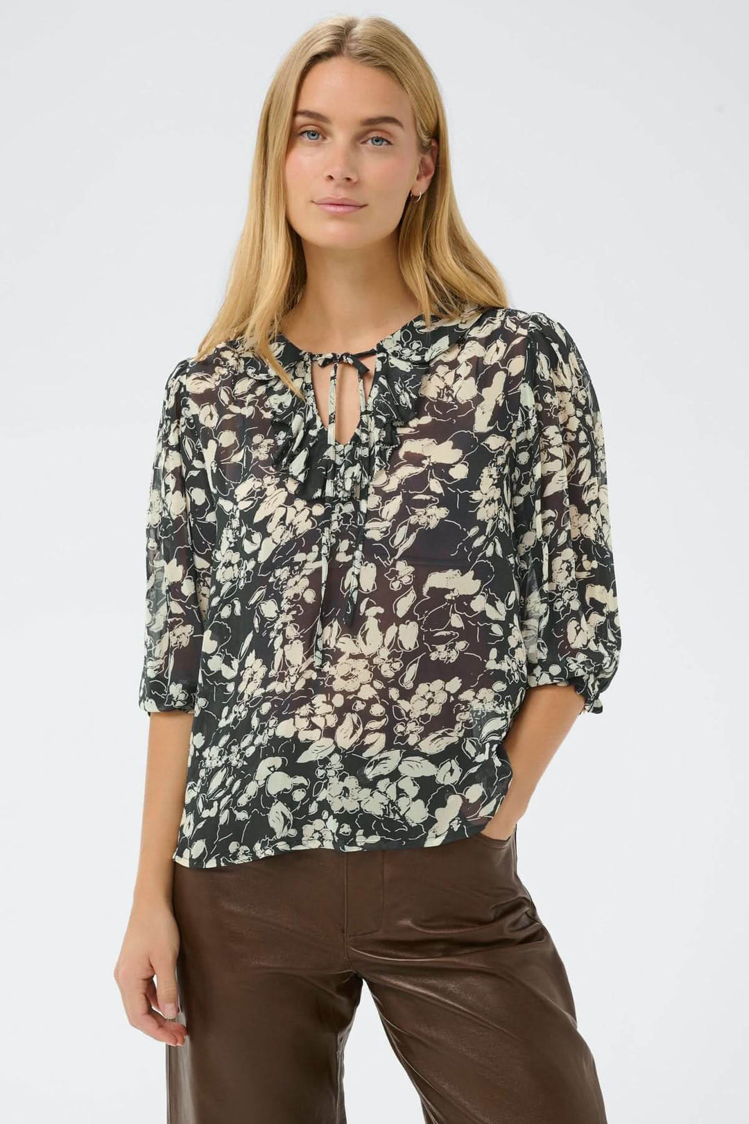 Blouse fluide à volants Alvia avec motif floral, portée par une femme, illustrant élégance et légèreté. Style décontracté et féminin.