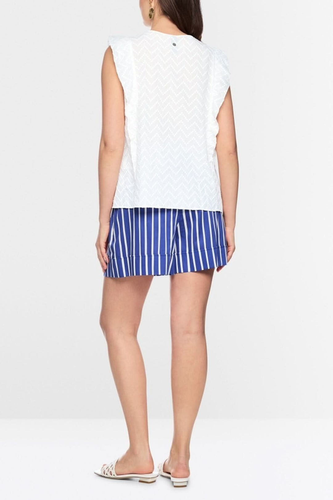 Femme portant une blouse féminine avec volants, sans manches, silhouette fluide, style estival, de dos, coupe ample, sur fond blanc.