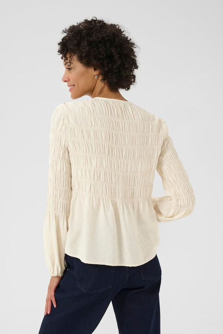 Blouse à fronces blanche avec encolure ronde et détails texturés, vue de dos, portée avec un jean pour un style casual chic.