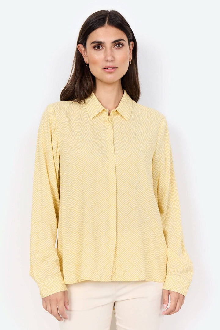 Blouse imprimée jaune à col classique et motifs géométriques, idéale à porter avec un pantalon ajusté.