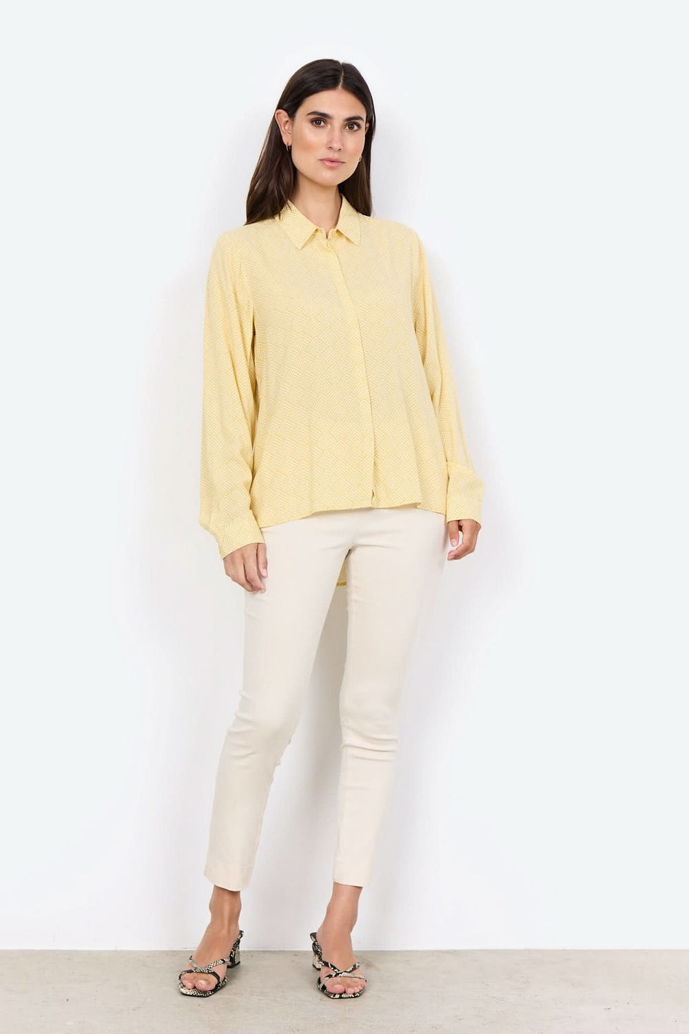 Chemise jaune à col classique, boutonnière, portée avec un pantalon blanc, style décontracté chic.