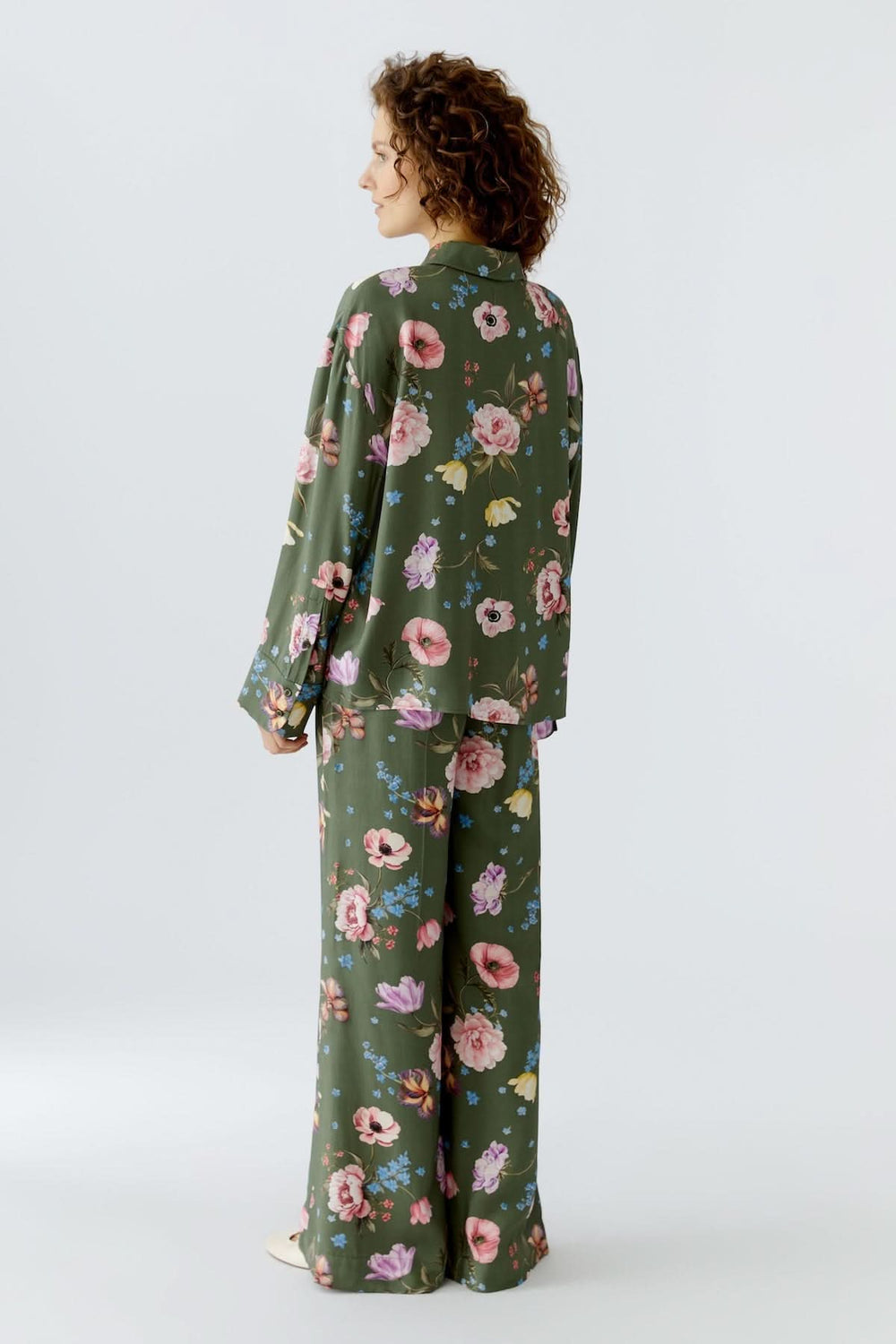 Femme portant une blouse à imprimé floral fluide avec manches longues et col chemise classique, design féminin et moderne.