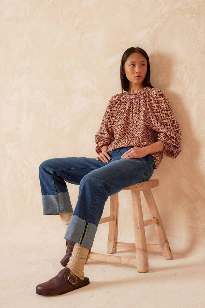 Blouse imprimé mosaïque à manches longues portée avec un pantalon en denim, pour un style moderne.