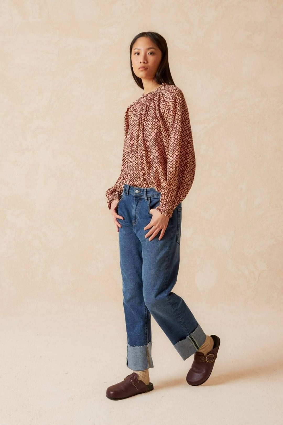 Blouse imprimée mosaïque à manches longues, portée avec un pantalon en denim pour un look moderne et casual.