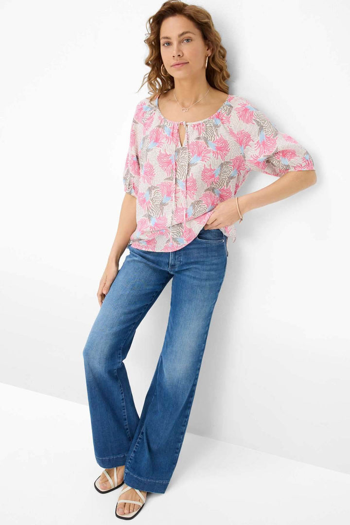 Femme portant la blouse imprimée VIVA, légère et fluide, assortie à un jean évasé, style décontracté.