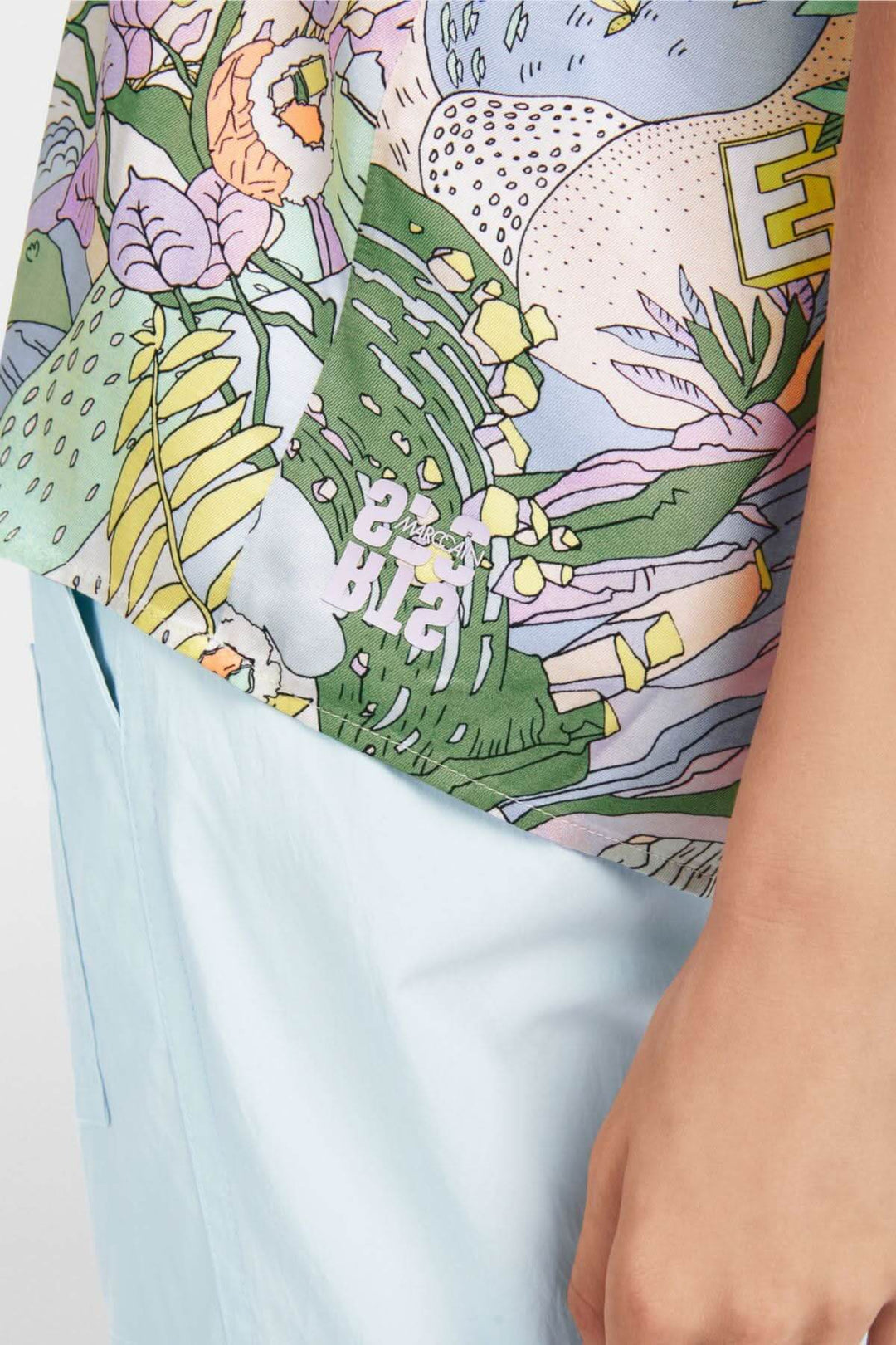 Détail d'une blouse imprimée sushi colorée avec motifs floraux et un design ample et fluide.