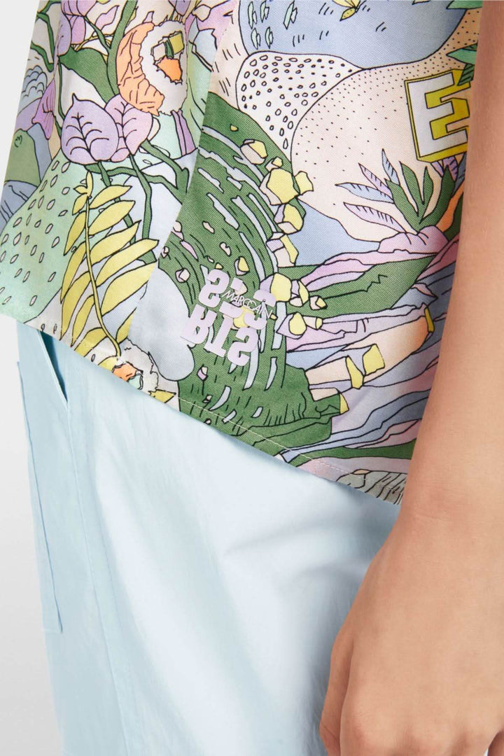 Détail d'une blouse imprimée sushi colorée avec motifs floraux et un design ample et fluide.