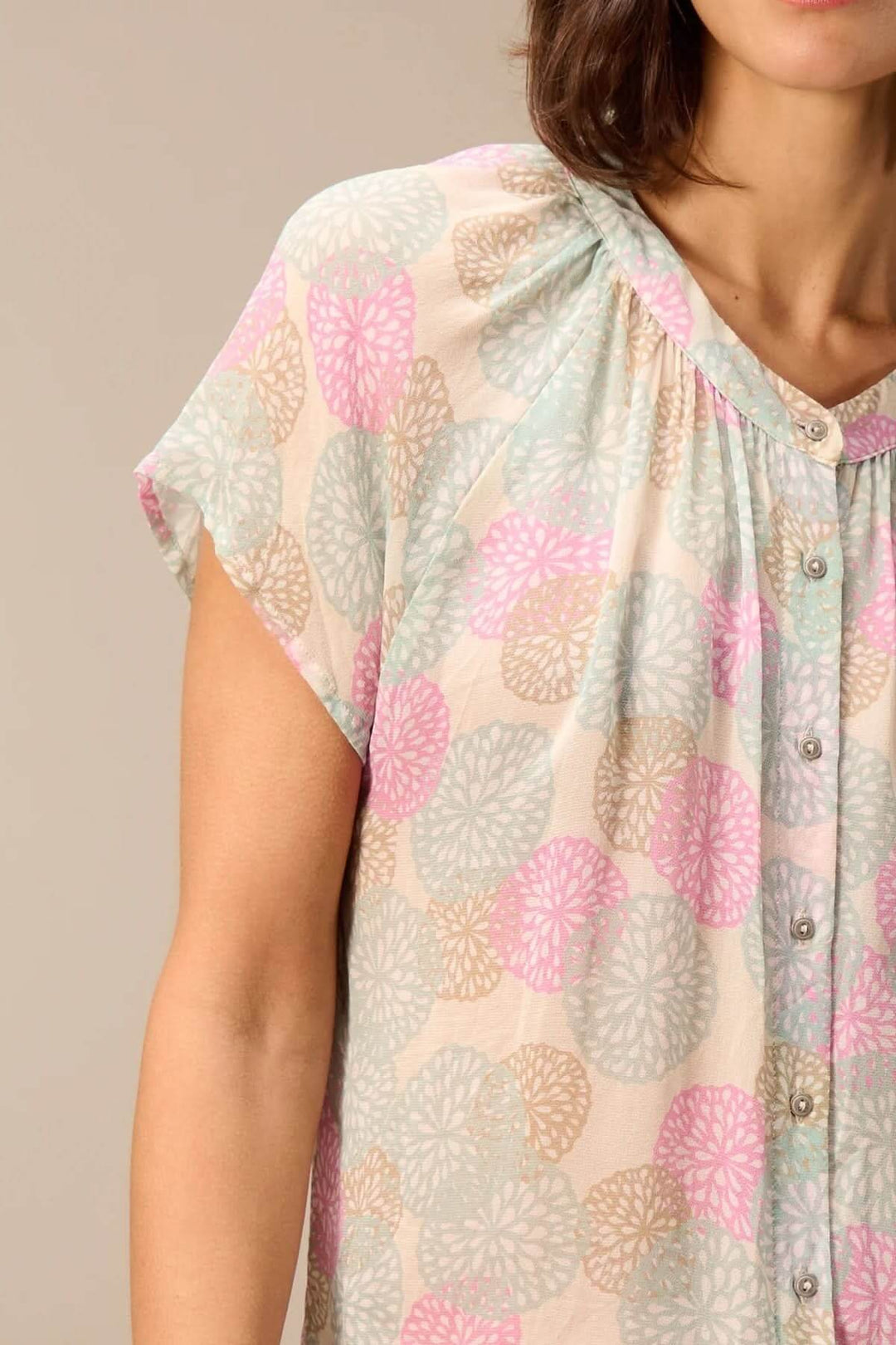 Blouse légère à manches courtes avec imprimé floral coloré, encolure ronde et boutons sur le devant, tenue estivale élégante.