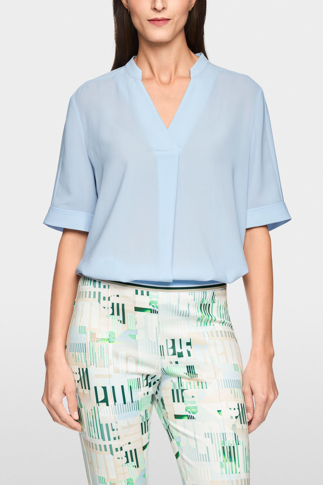 Blouse à manches courtes avec encolure en V subtilement structurée, offrant un style moderne et minimaliste.